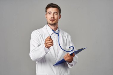Stüdyo çekimi. Gri arka planda izole edilmiş genç doktor konuşuyor. 
