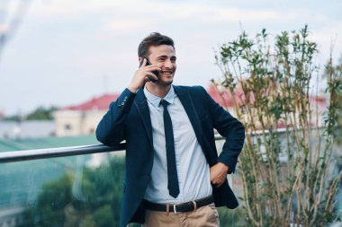 Genç yakışıklı işadamı sokakta akıllı telefondan konuşuyor. 