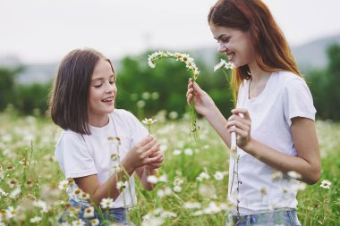 Genç anne ve kızı papatya tarlasında eğleniyorlar.