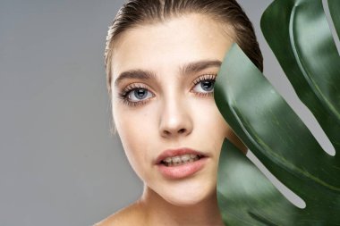 Stüdyoda yaprak ile poz veren genç güzel model.