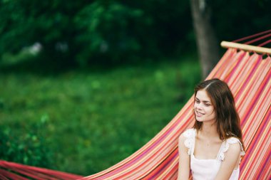 Genç ve güzel bir kadın hamakta dinleniyor.