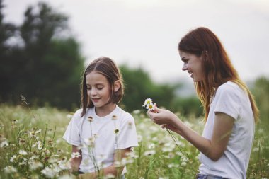 Genç anne ve kızı papatya tarlasında eğleniyorlar.