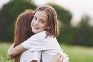 Genç anne ve kızı papatya tarlasında eğleniyorlar.