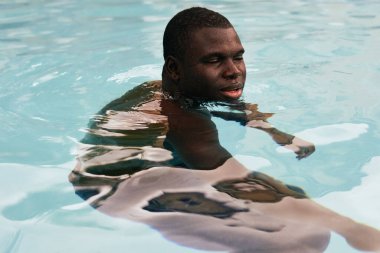 Havuzda poz veren genç yakışıklı adam.