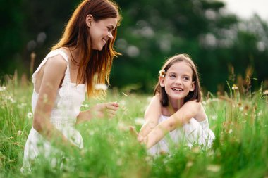 Genç anne ve kızı papatya tarlasında eğleniyorlar.