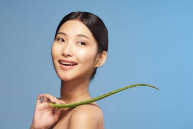 Genç güzel Asyalı kadın aloe vera yaprağıyla poz veriyor. 