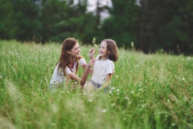 Genç anne ve kızı papatya tarlasında eğleniyorlar.