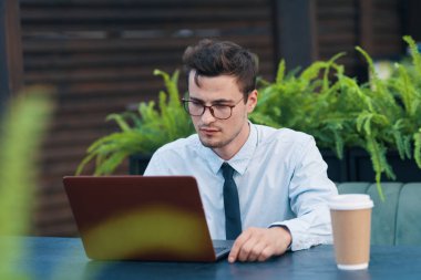 Kafede dizüstü bilgisayarla çalışan yakışıklı bir iş adamı.