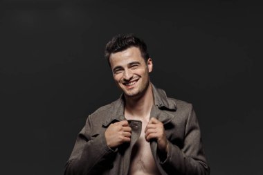 Stüdyoda poz veren ceketli genç yakışıklı adam.