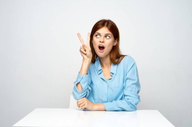 Genç ve güzel bir iş kadını zafer jesti ile ofiste oturuyor. 