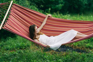 Genç ve güzel bir kadın hamakta dinleniyor. 