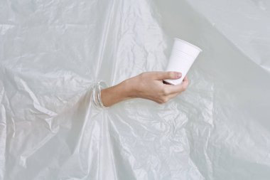 Plastik ve polietilen yırtıklar olan bir kadın eli.