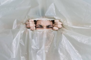 Plastik ve polietilen yırtan genç bir kadın.