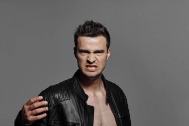 Stüdyoda poz veren siyah deri ceketli kızgın genç adamın portresi.. 