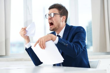 Ofisinde belgeleri olan kızgın genç bir işadamı. 