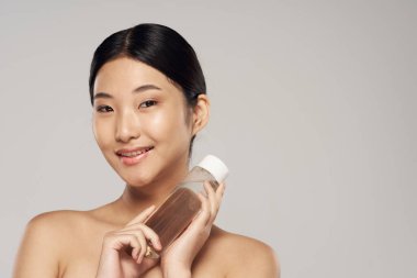 beautiful asian woman holding bottle, beauty product 