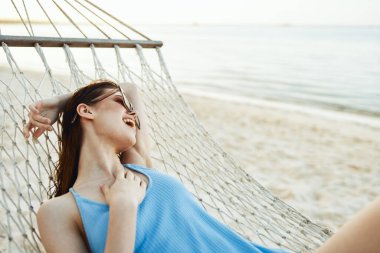 Genç ve güzel bir kadın hamakta dinleniyor.