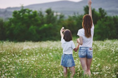 Genç anne ve kızı papatya tarlasında eğleniyorlar.