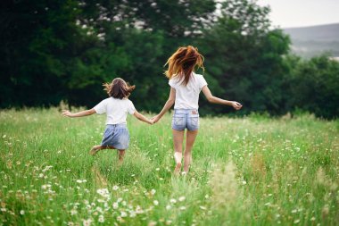 Genç anne ve kızı papatya tarlasında eğleniyorlar.