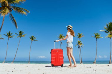  Kumsalda kırmızı valizli genç bir kadın.