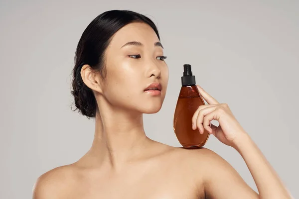 Young asian woman with hair spray in studio. Beauty, fashion photography