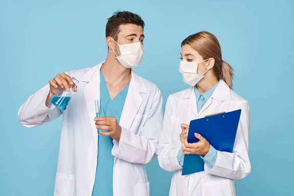 Stodio shot of young doctors  in masks with test tubes