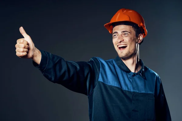 young man in work wear and helmet showing thumb up. Studio shot