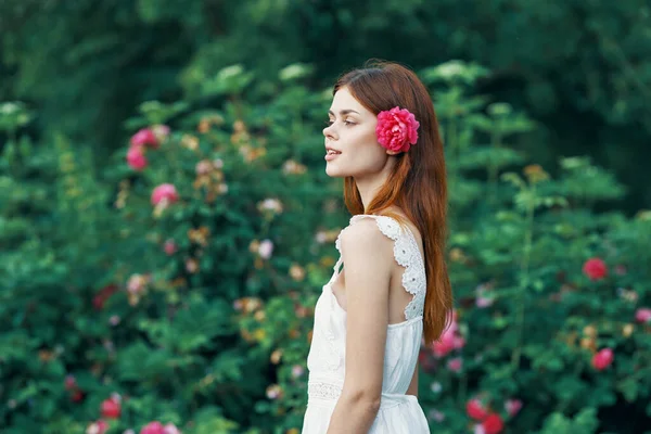 庭にバラの花を持つ若い女性 — ストック写真