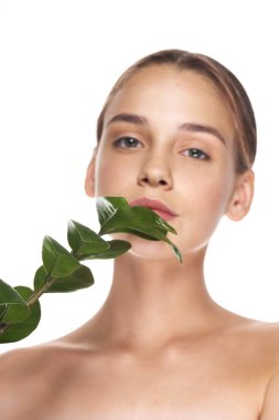 Stüdyoda yaprağıyla poz veren genç ve güzel bir kadın.