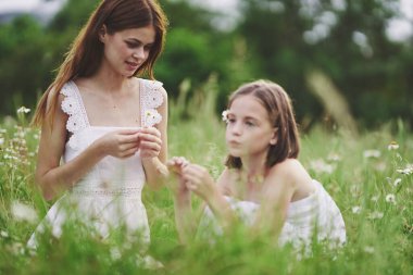 Genç anne ve kızı papatya tarlasında eğleniyorlar.