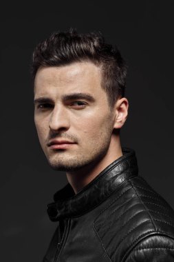 Stüdyoda poz veren siyah deri ceketli yakışıklı bir adamın portresi.. 