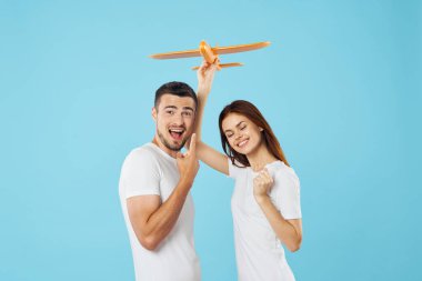 Genç ve güzel bir çift mavi arka planda sarı oyuncak uçakla oynuyor. 