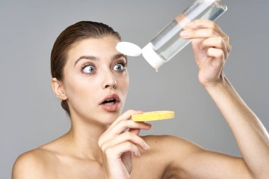 Genç ve güzel bir kadın cildini sünger ve mikiler suyuyla temizliyor. 