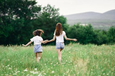 Genç anne ve kızı papatya tarlasında eğleniyorlar.