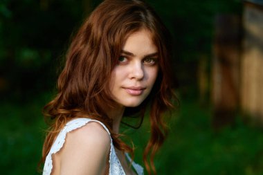 Yaz bahçesinde poz veren güzel bir kadın. 