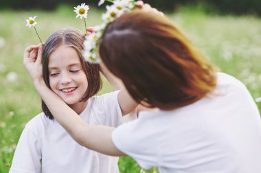 Genç anne ve kızı papatya tarlasında eğleniyorlar.