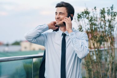 Genç yakışıklı işadamı akıllı telefondan konuşuyor.