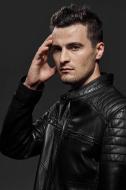 Stüdyoda poz veren siyah deri ceketli yakışıklı bir adamın portresi.. 