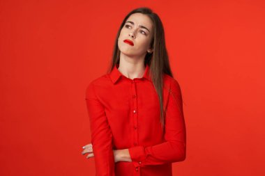 Stüdyo çekimi. Kırmızılı güzel üzgün kadın kırmızı arka planda izole edilmiş.