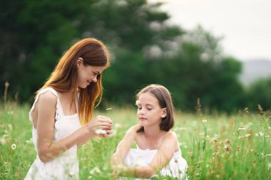 Genç anne ve kızı papatya tarlasında eğleniyorlar.