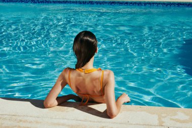 Genç ve güzel bir kadın havuzda dinleniyor.  