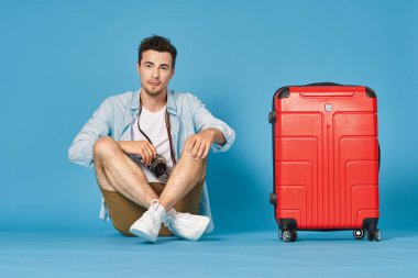 Fotoğraf makinesi ve çantalı genç turistin stüdyo fotoğrafı.