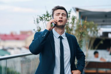 Akıllı telefonlu genç, yakışıklı, yorgun iş adamı. 