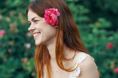 Bahçesinde gül çiçeği olan genç bir kadın