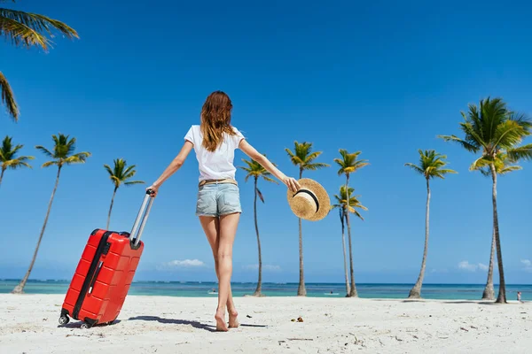 若いです女性とともに赤いスーツケースオンビーチ — ストック写真