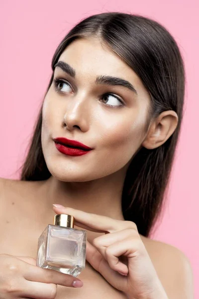 Portrait of young beautiful  woman with perfume bottle. Studio shot