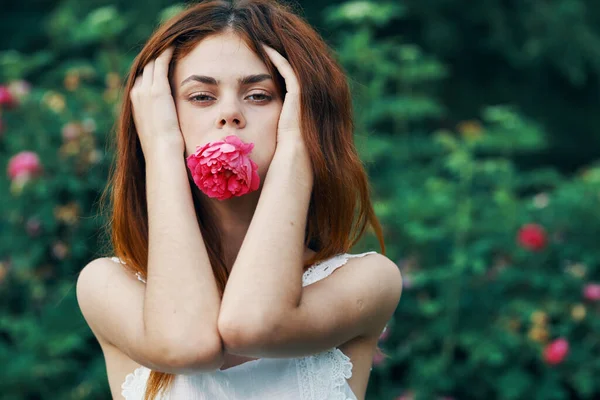 庭にバラの花を持つ若い女性 — ストック写真