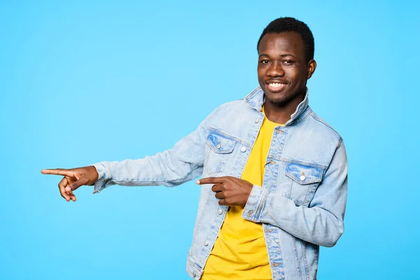 Young  happy man showing something   isolated on blue background