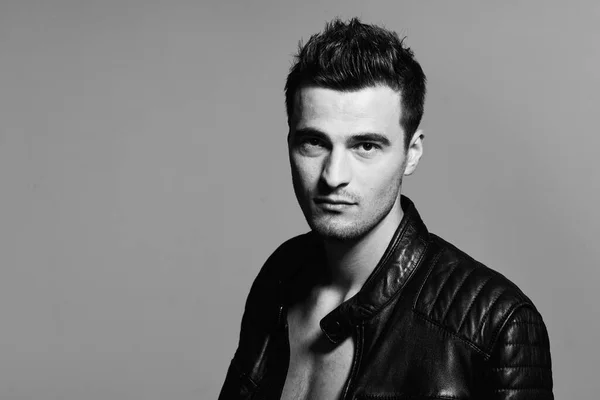 Young handsome man in leather jacket posing in studio. Black and white