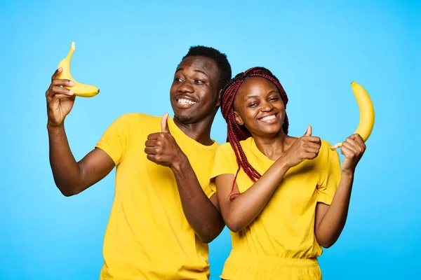 man and woman of african appearance  with bananas showing thumbs up   on isolated background